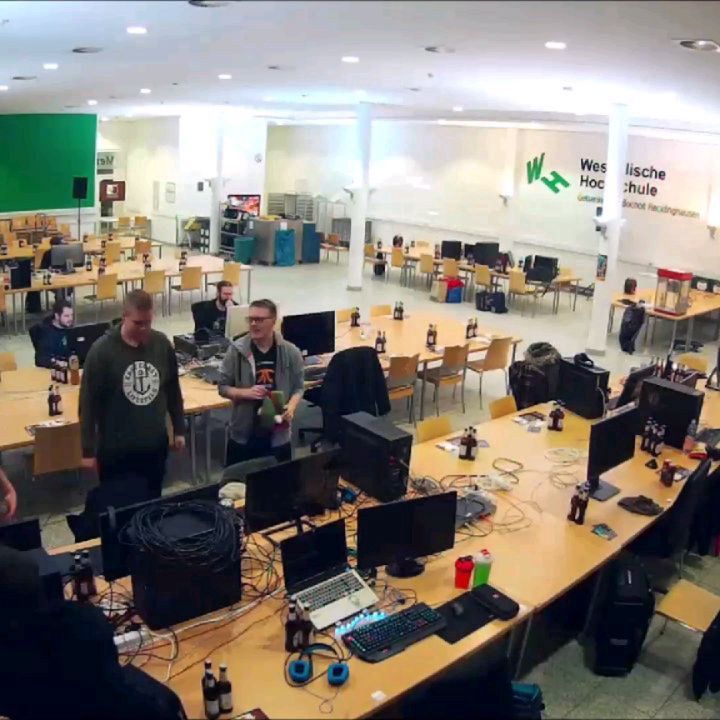 Mehrere Personen stehen zwischen aufgebauten Computern und Monitoren an den langen Tischreihen der Mensa.